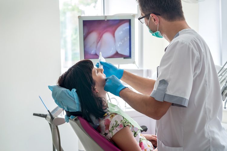 Doctor examining patient's teeth with intraoral camera